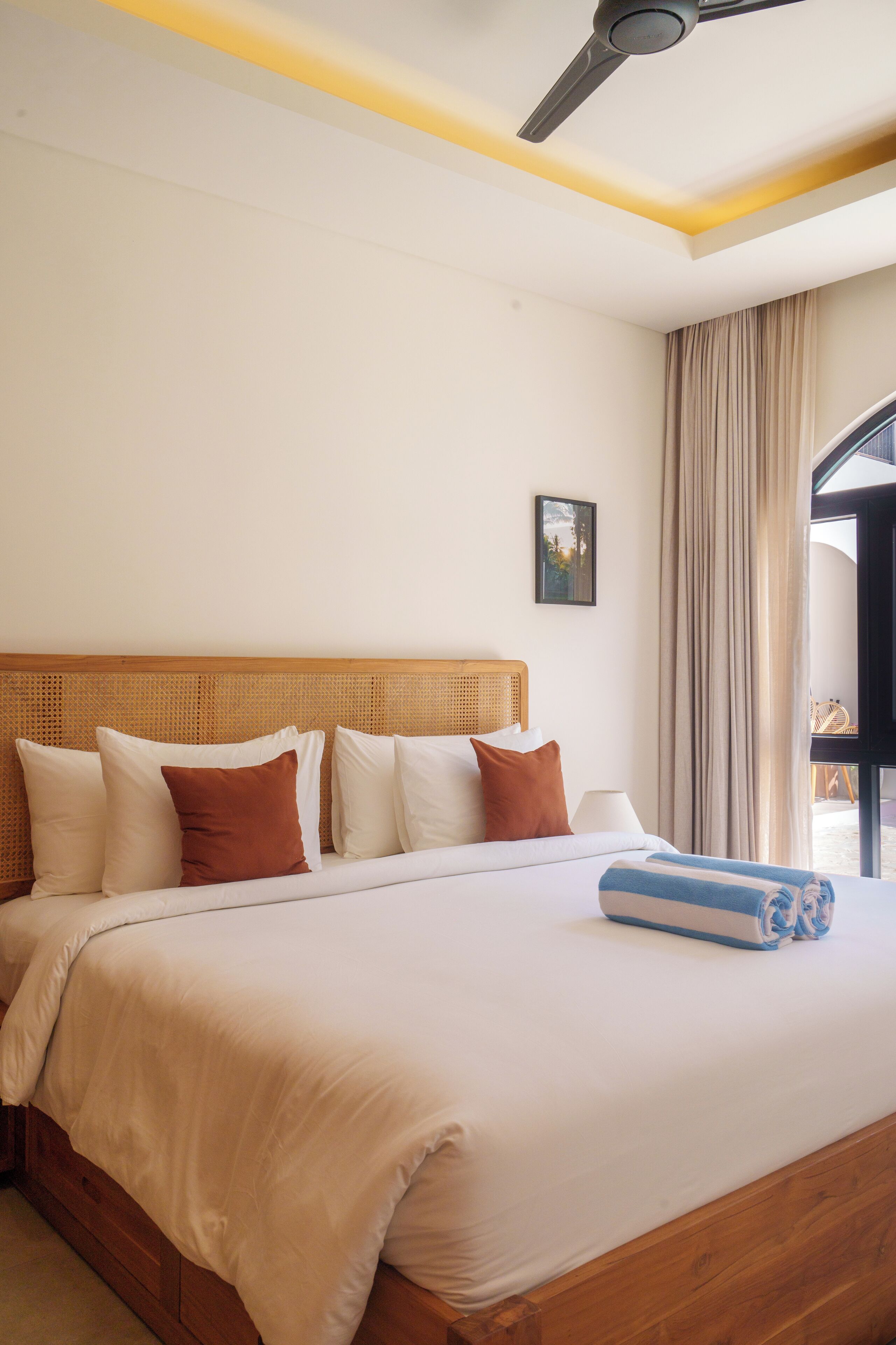 A hotel room with a large bed, wooden headboard, and a ceiling fan.
