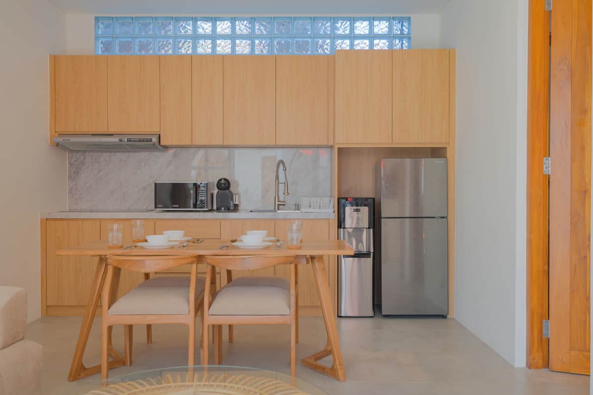 A modern kitchen with wooden cabinets, a stainless steel refrigerator, and a dining table with chairs.