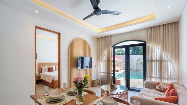 Une chambre d’hôtel moderne dotée d’un coin repas, d’un canapé, d’une télévision et offrant une vue sur l’extérieur.