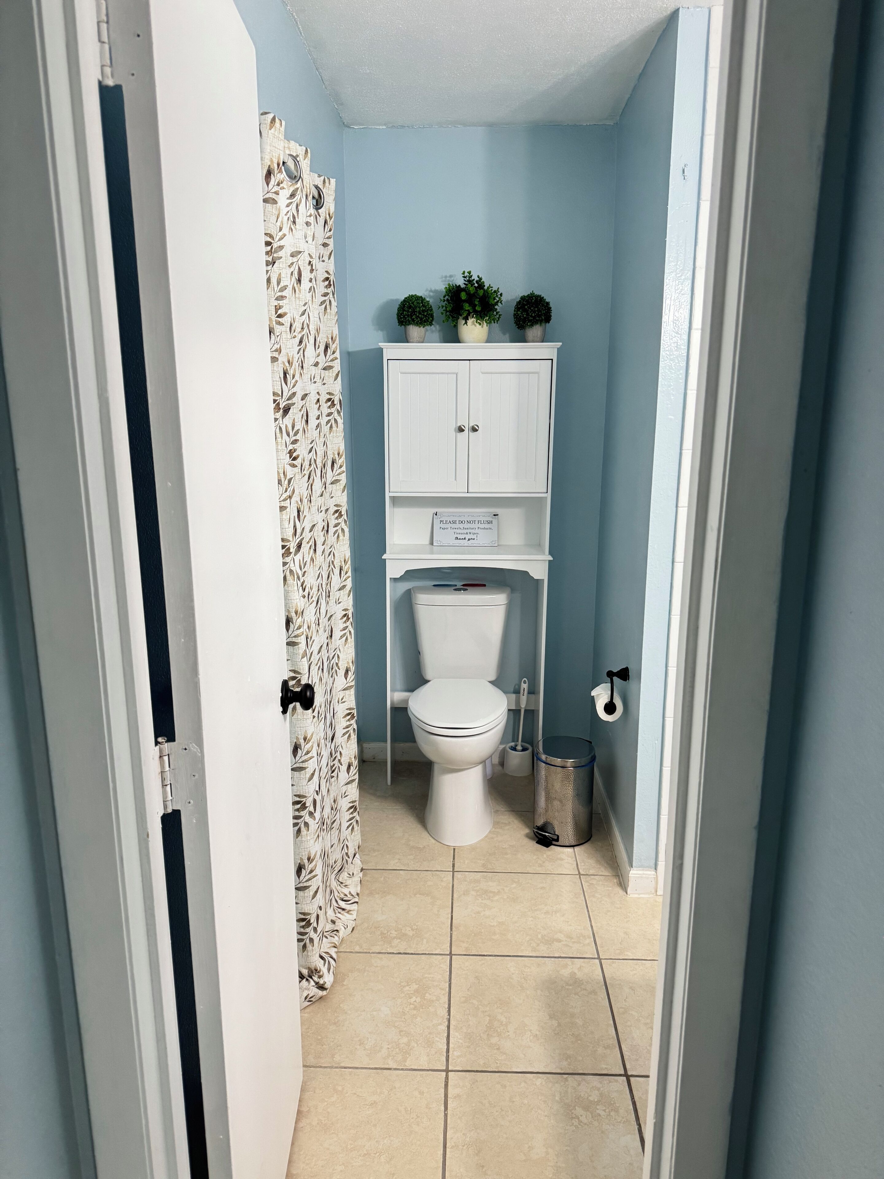 Un baño con inodoro, un armario y un bote de basura.