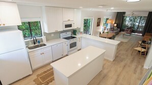Une cuisine moderne avec des meubles blancs, un îlot central et un coin repas comprenant une table et des chaises.