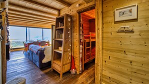 Een gezellig houten interieur met een slaapstapelbed, een boekenkast en een groot raam met uitzicht.
