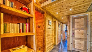 Een houten interieur met boekenkasten, een open haard en een gang naar een deur.
