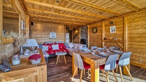 Een gezellig houten blokhut interieur met een eethoek, een bank en een open haard.