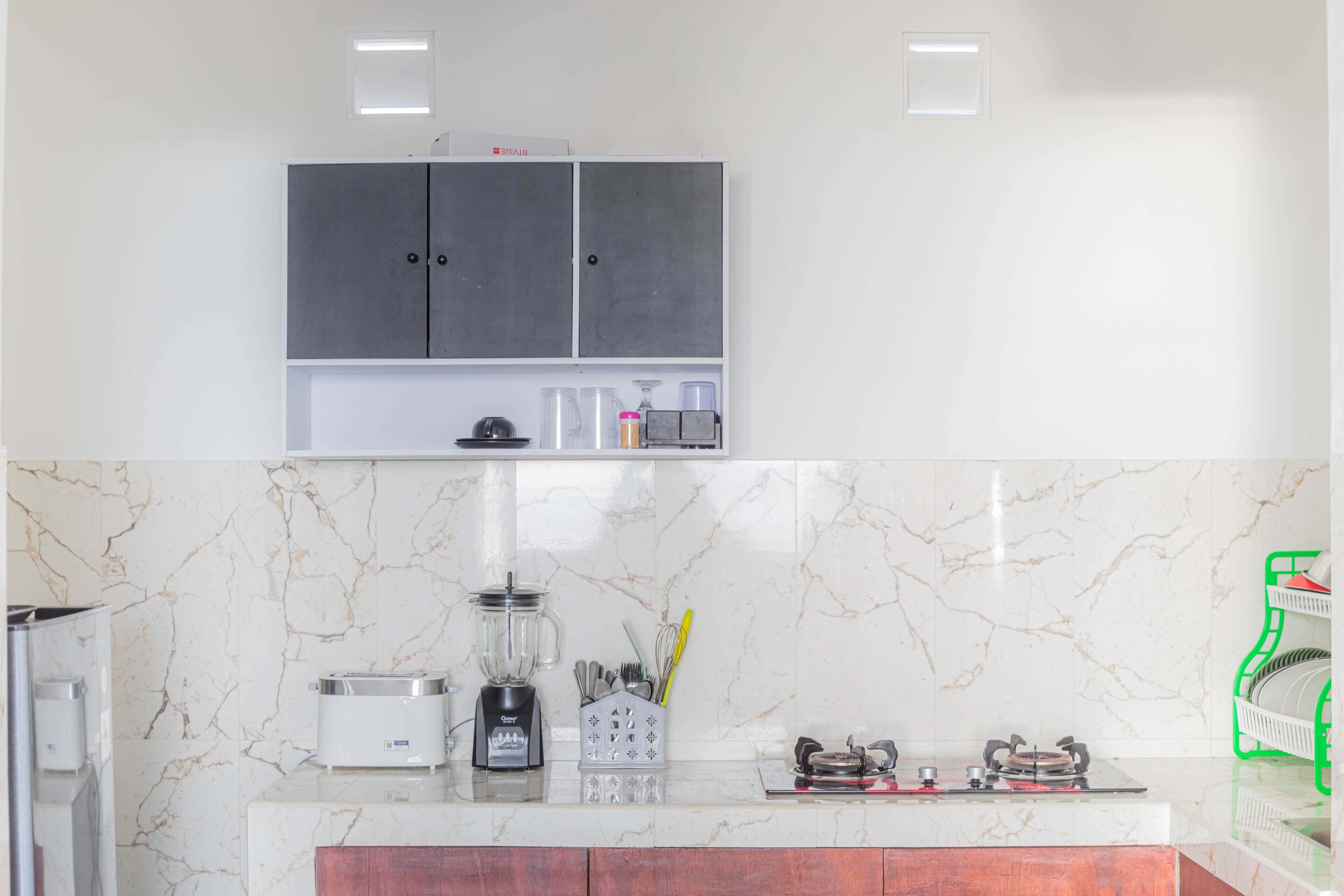 A kitchen with a marble backsplash, a built-in oven, a coffee maker, and a blender on the counter.