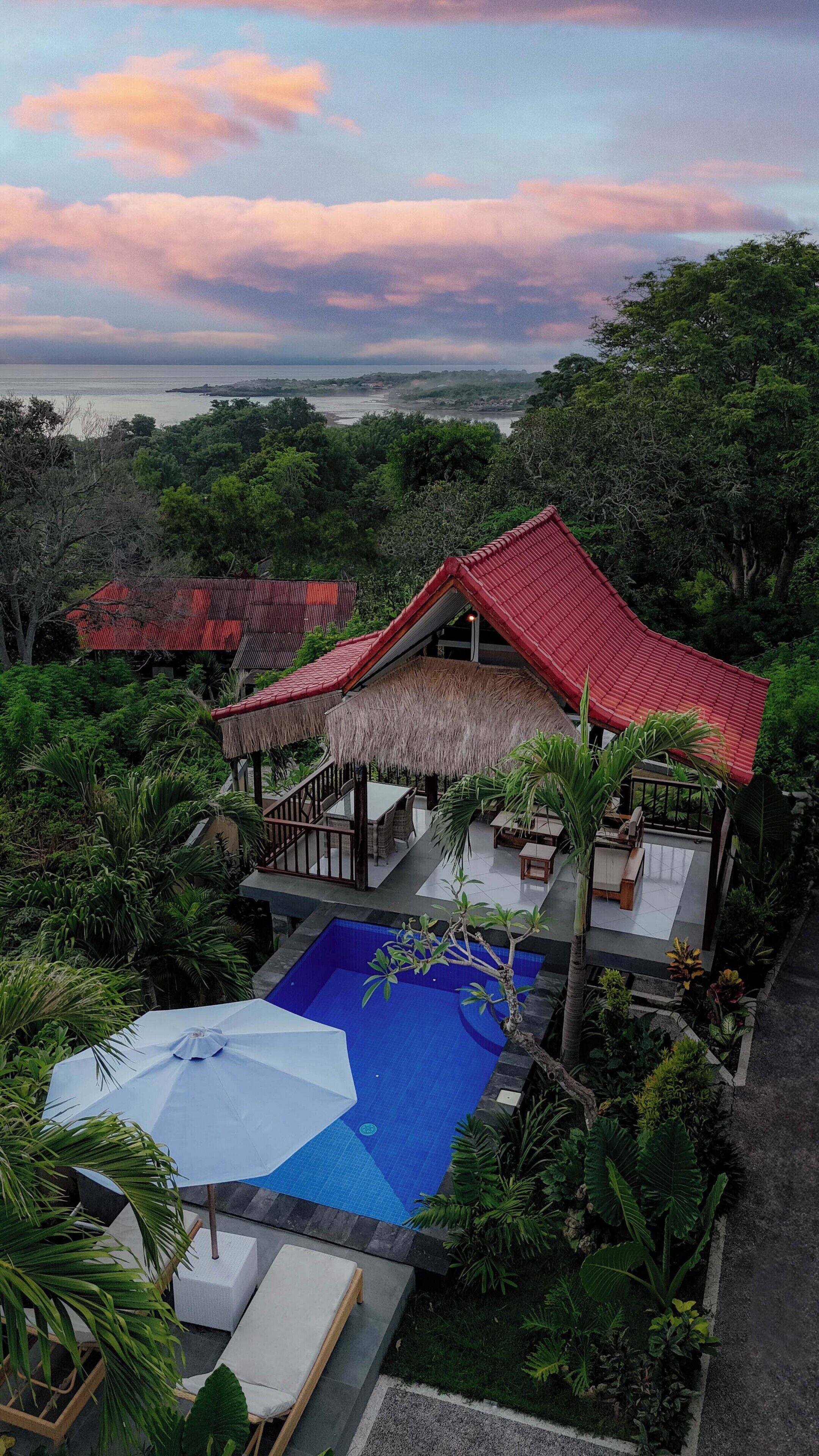 A resort with a swimming pool, outdoor seating, and a view of the sea.