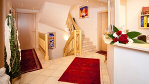 Un escalier avec une rampe en bois menant à un palier recouvert d’une moquette rouge.