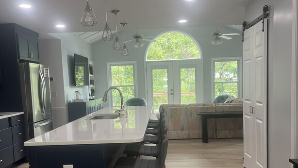 Una cocina moderna con una isla central, taburetes de bar y una zona de comedor con banco.
