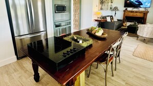 A modern kitchen with a black induction cooktop, stainless steel appliances, and a wooden dining table. - Private, serene cottage on a horse ranch w/ spa vibes, near Granbury & Ft Worth. (Granbury)