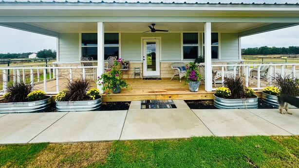 A covered porch with a welcome mat, potted plants, and outdoor furniture. - Private, serene cottage on a horse ranch w/ spa vibes, near Granbury & Ft Worth. (Granbury)