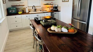 A modern kitchen with white cabinets, a wooden countertop, a stainless steel refrigerator, and a variety of kitchen appliances. - Private, serene cottage on a horse ranch w/ spa vibes, near Granbury & Ft Worth. (Granbury)