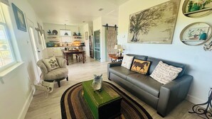A living room with a sofa, armchairs, a coffee table, and a dining area with a table and chairs. - Private, serene cottage on a horse ranch w/ spa vibes, near Granbury & Ft Worth. (Granbury)