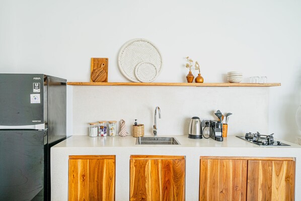 Una cucina con frigorifero, mobili in legno, lavandino e diversi oggetti da cucina sul piano di lavoro.