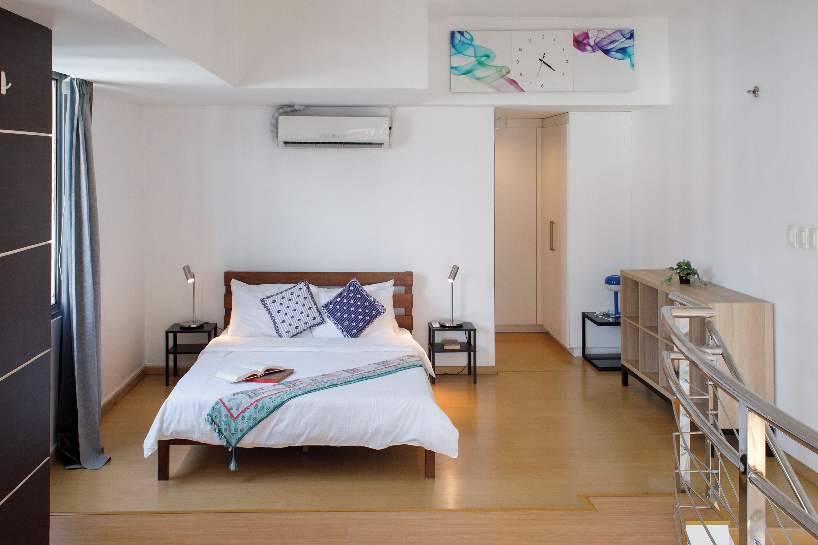 A modern bedroom with a wooden bed, two bedside tables, a nightstand, a ceiling fan, and a view of the hallway.