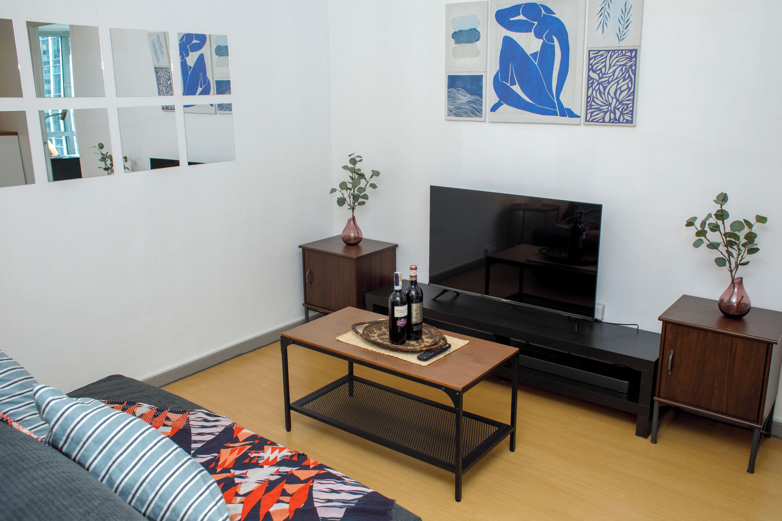 A living room with a sofa, a coffee table, a TV, and two side tables with vases.