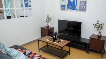 Un salon comprenant un canapé, une table basse, un téléviseur et deux petites tables d’appoint sur lesquelles sont posés des vases.
