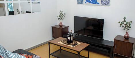 A living room with a sofa, a coffee table, a TV, and two side tables with vases.