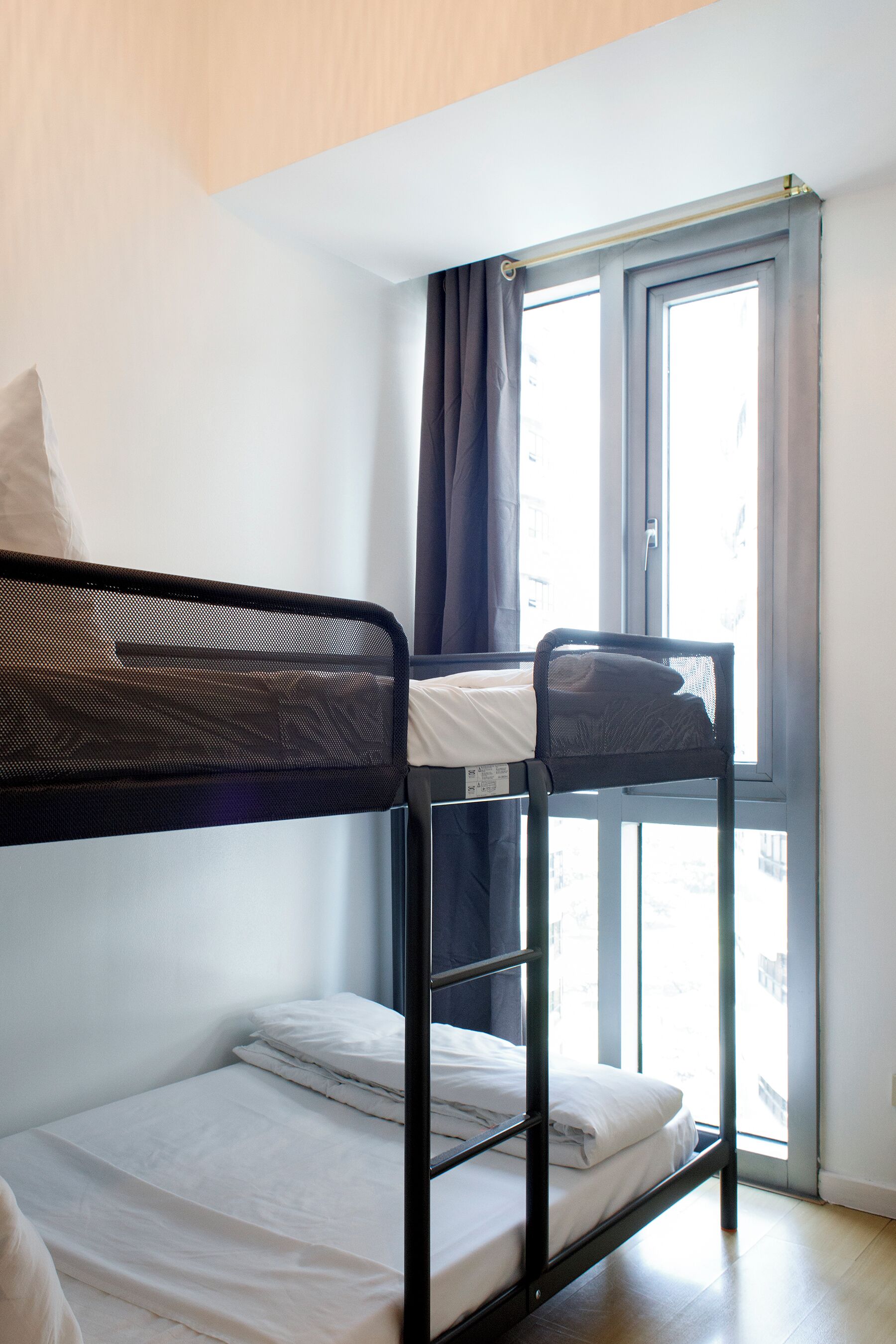 Een stapelbed met uitzicht uit het raam, een enkel bed en een hoofdbord.
