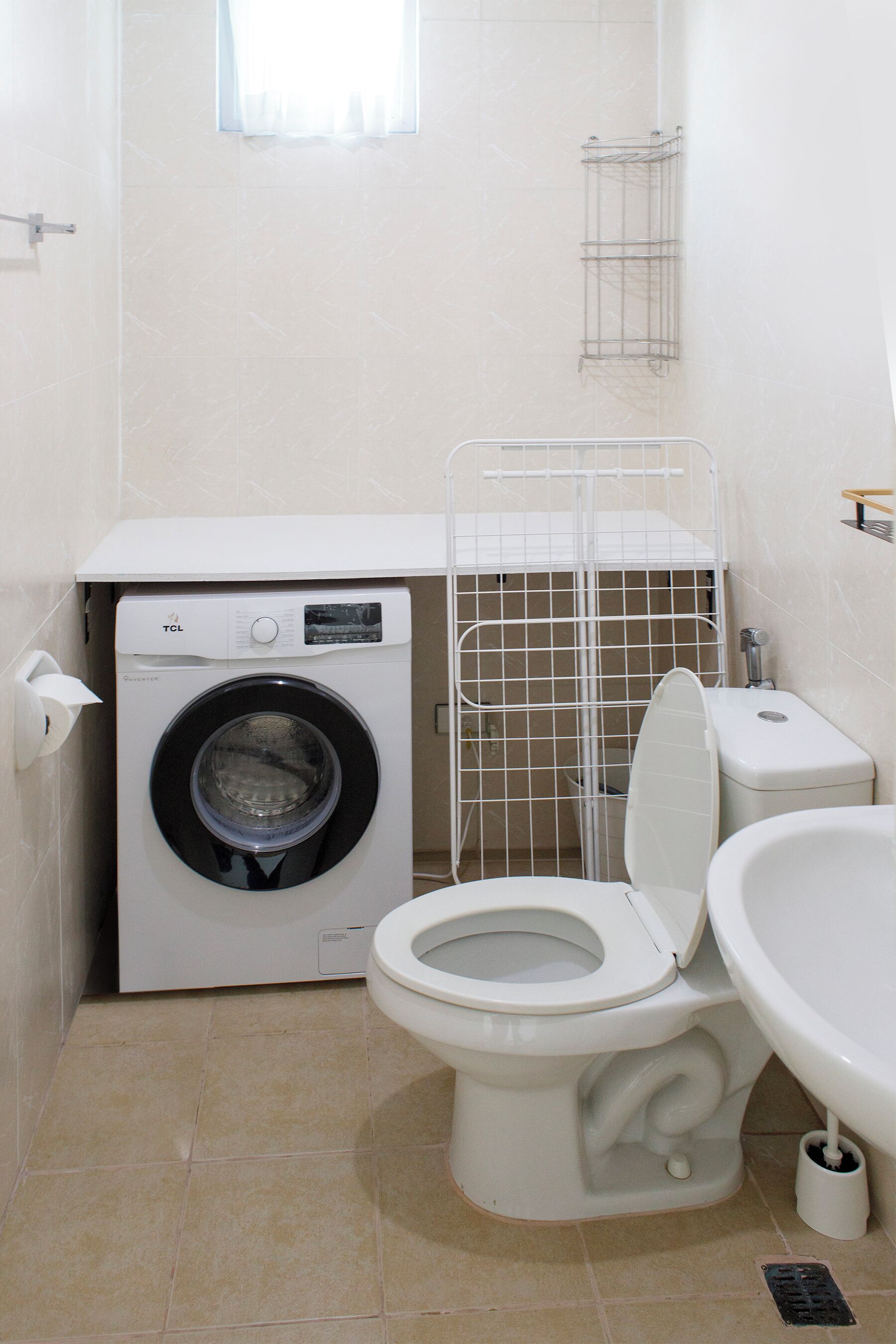 A compact bathroom with a washing machine, toilet, and sink.