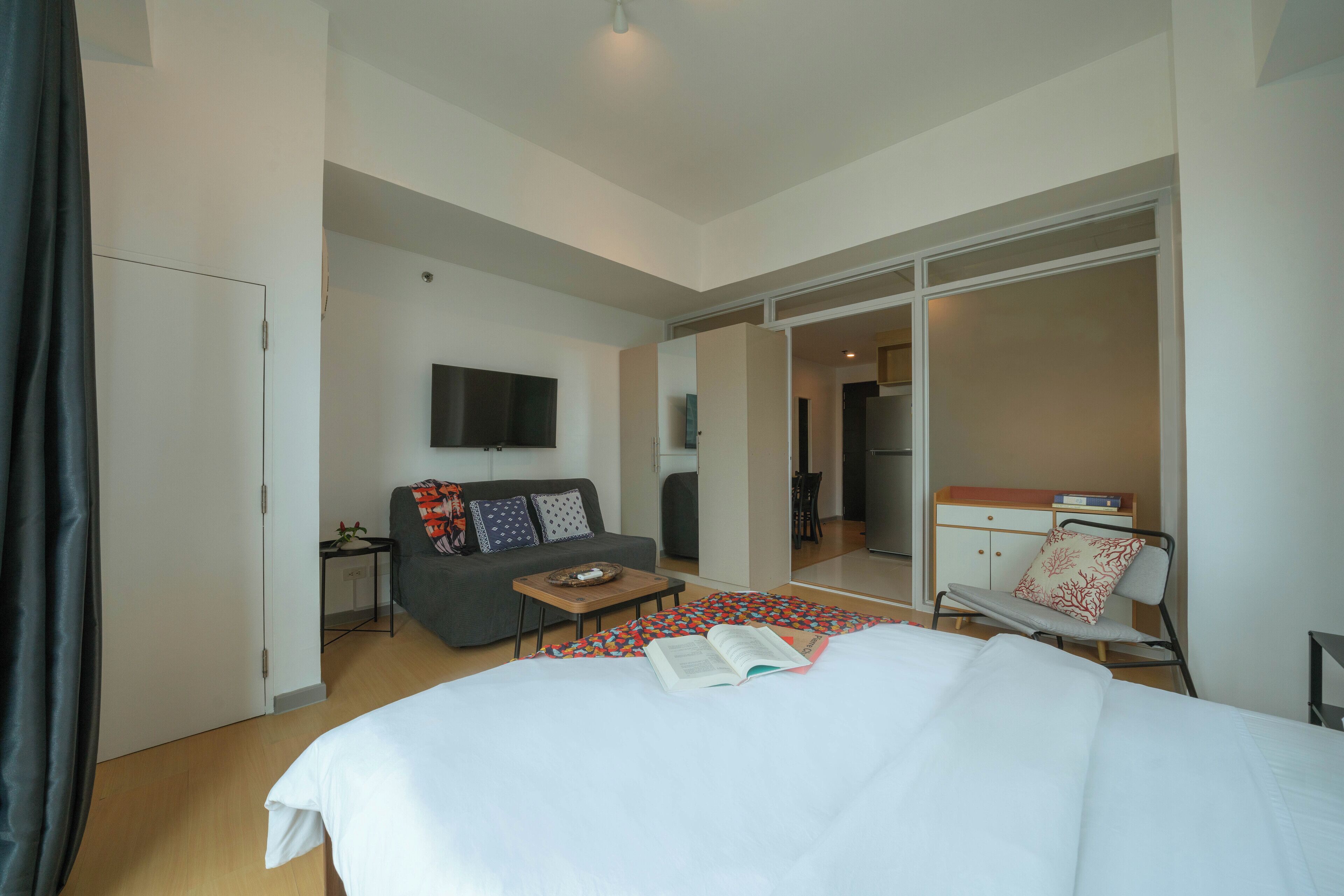 A hotel room with a bed, a sofa, a TV, a small table, and a chair.
