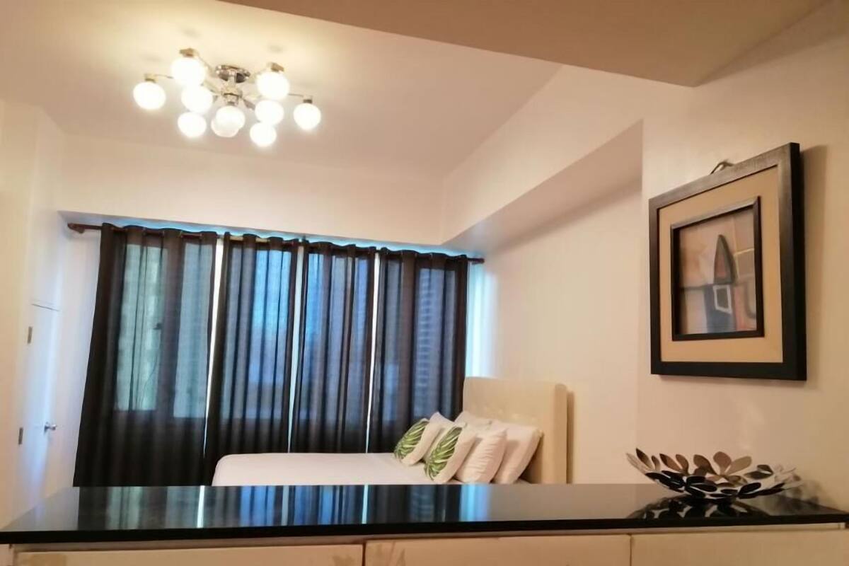 A bedroom with a bed, a nightstand, a framed picture on the wall, and a ceiling light fixture.