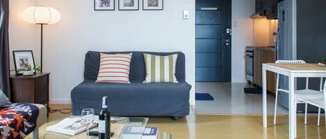 A modern living room with a sofa, coffee table, and a dining area with a table and chairs.