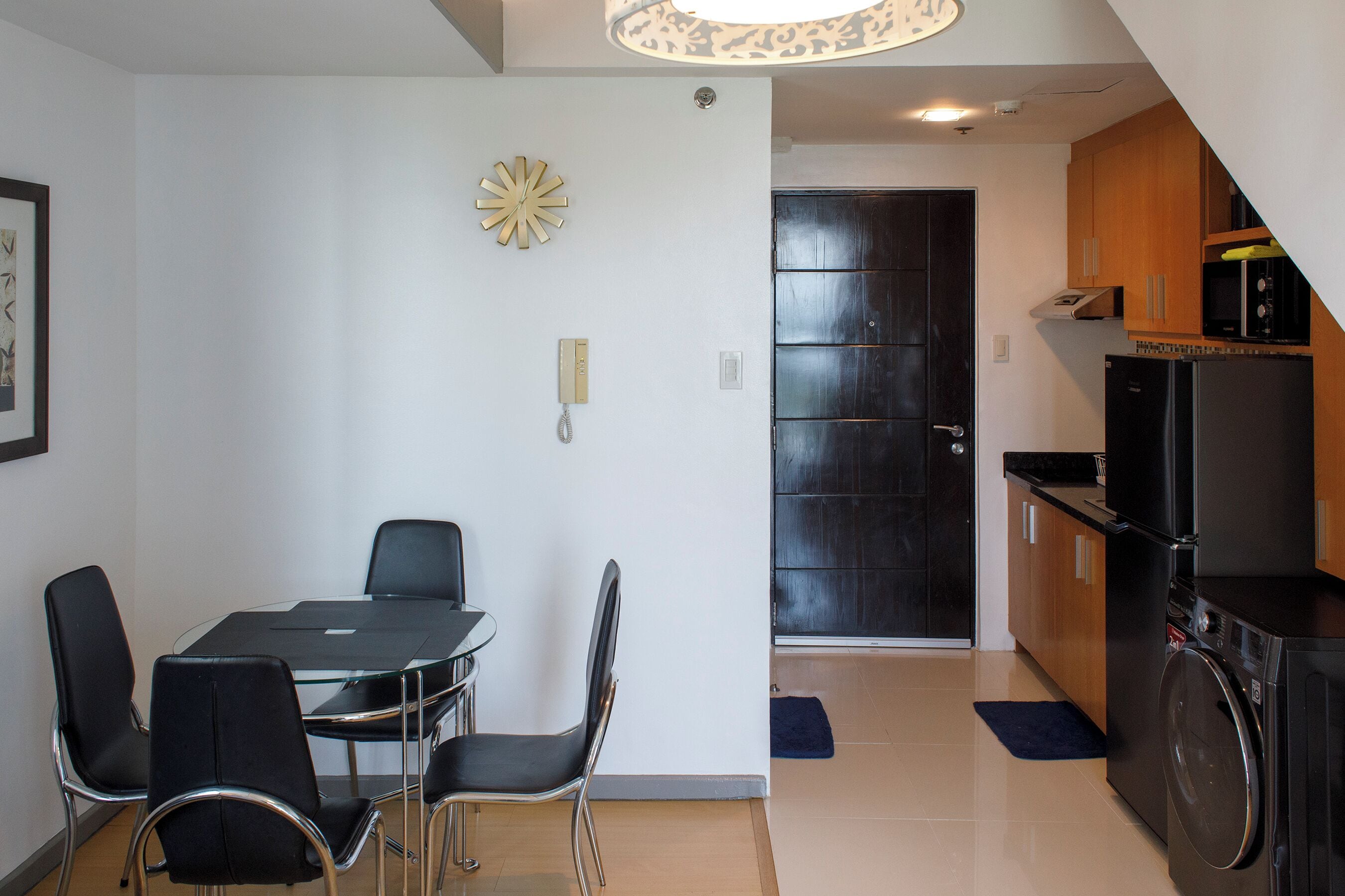 A compact living space with a dining area, kitchenette, and a door leading to another room.
