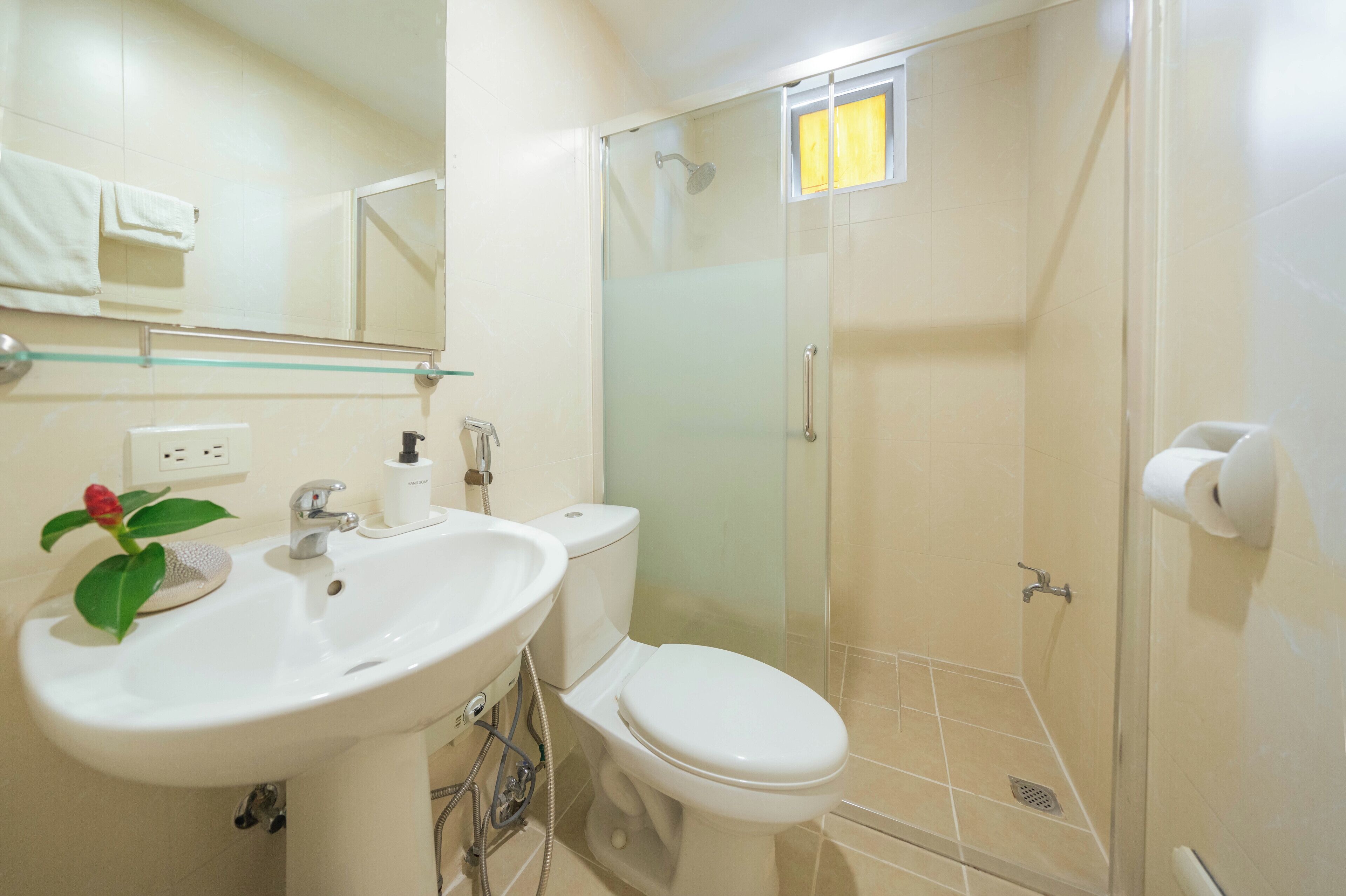 Un baño con lavamanos, inodoro y ducha con mampara de vidrio.