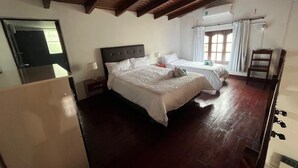 Ein Schlafzimmer mit zwei Betten, Holzdielenboden, Deckenbalken und einem Fenster mit Vorhängen.