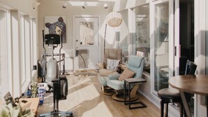 Un intérieur moderne avec un plafond haut, de grandes fenêtres et un espace salon central agrémenté d’une table et de chaises.