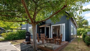 Una casa con porche cubierto, mobiliario exterior y una parrilla.