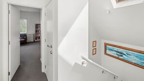 Un interior moderno con una escalera, una estantería y un cuadro.