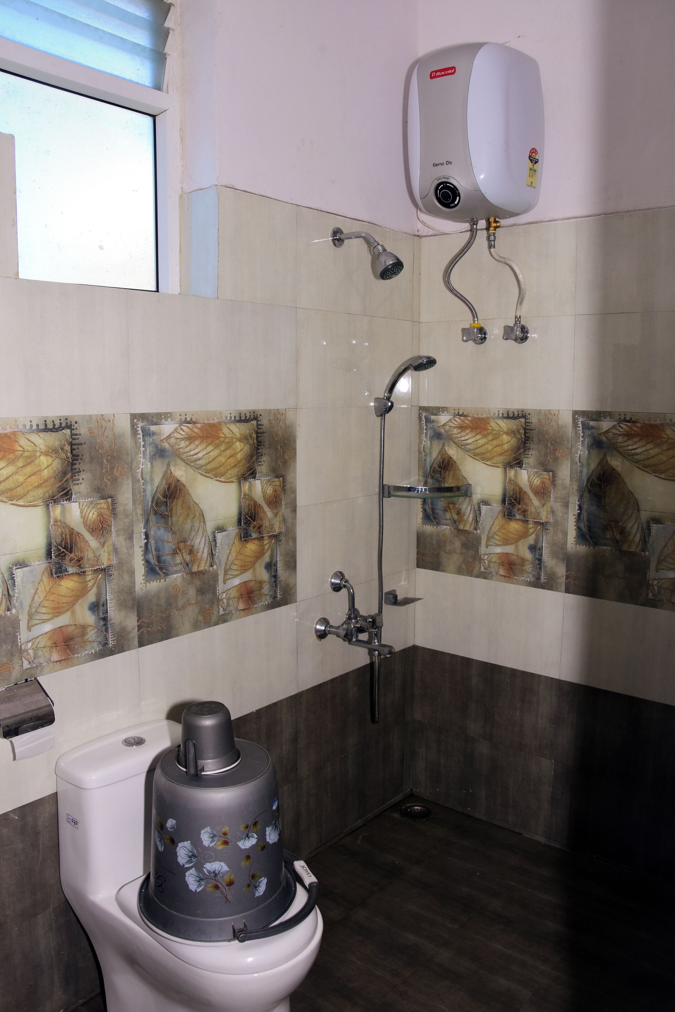 A bathroom with a toilet, a shower, and a hand dryer mounted on the wall.