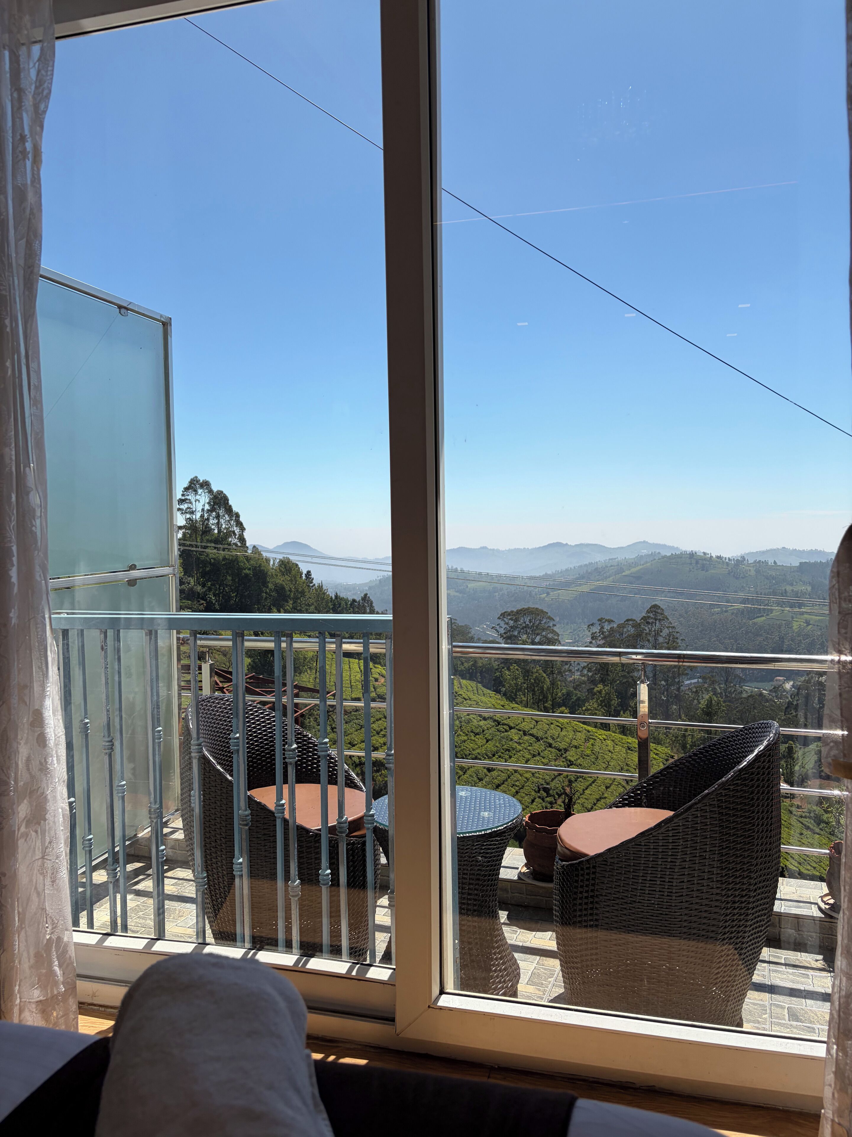 Ein Balkon mit Korbmöbeln und freiem Blick auf eine hügelige Landschaft.