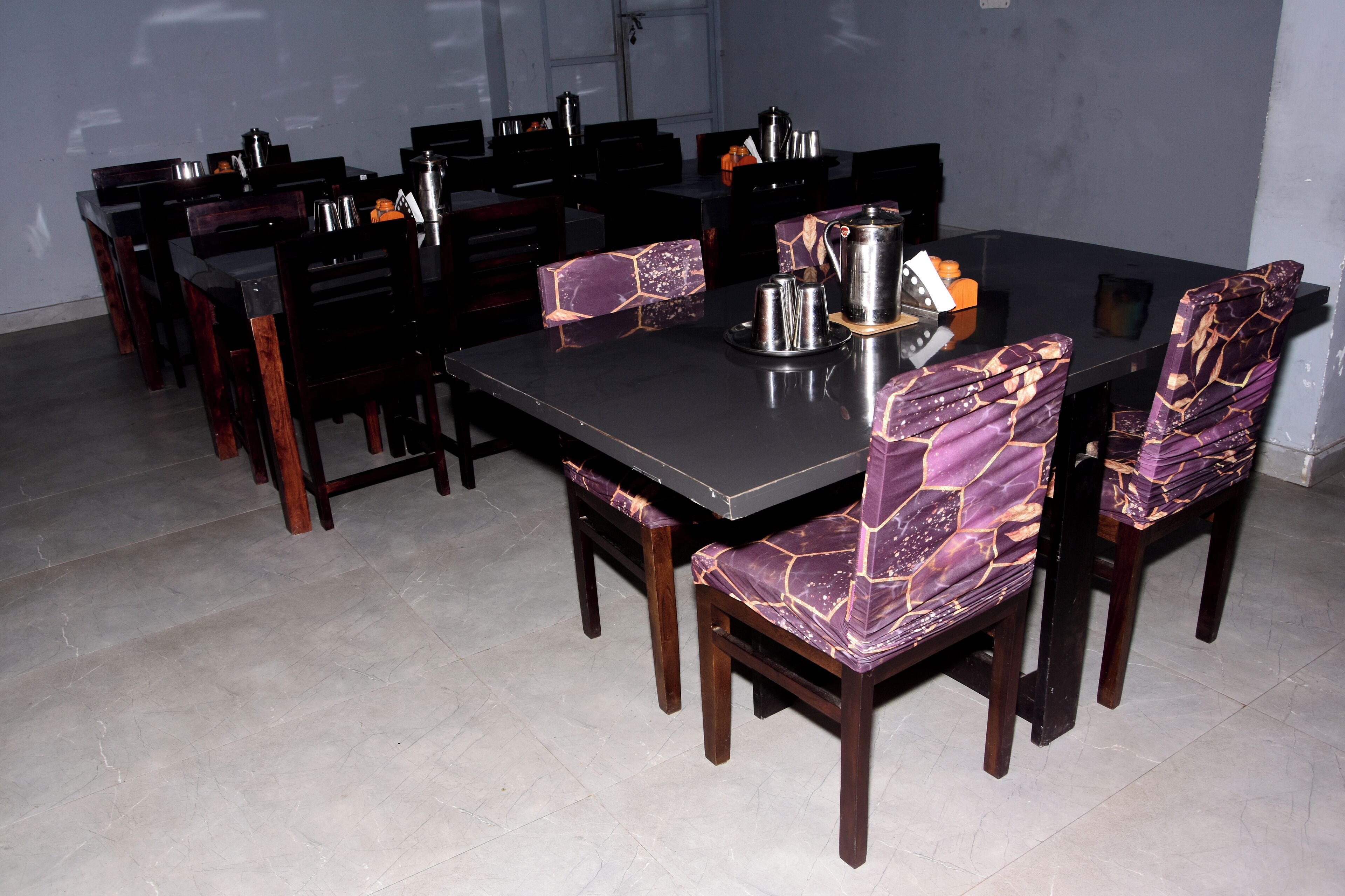 Un comedor con una mesa rectangular y sillas a juego, equipado con una cafetera y una bandeja.