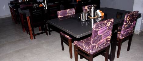 Un comedor con una mesa rectangular y sillas a juego, equipado con una cafetera y una bandeja.