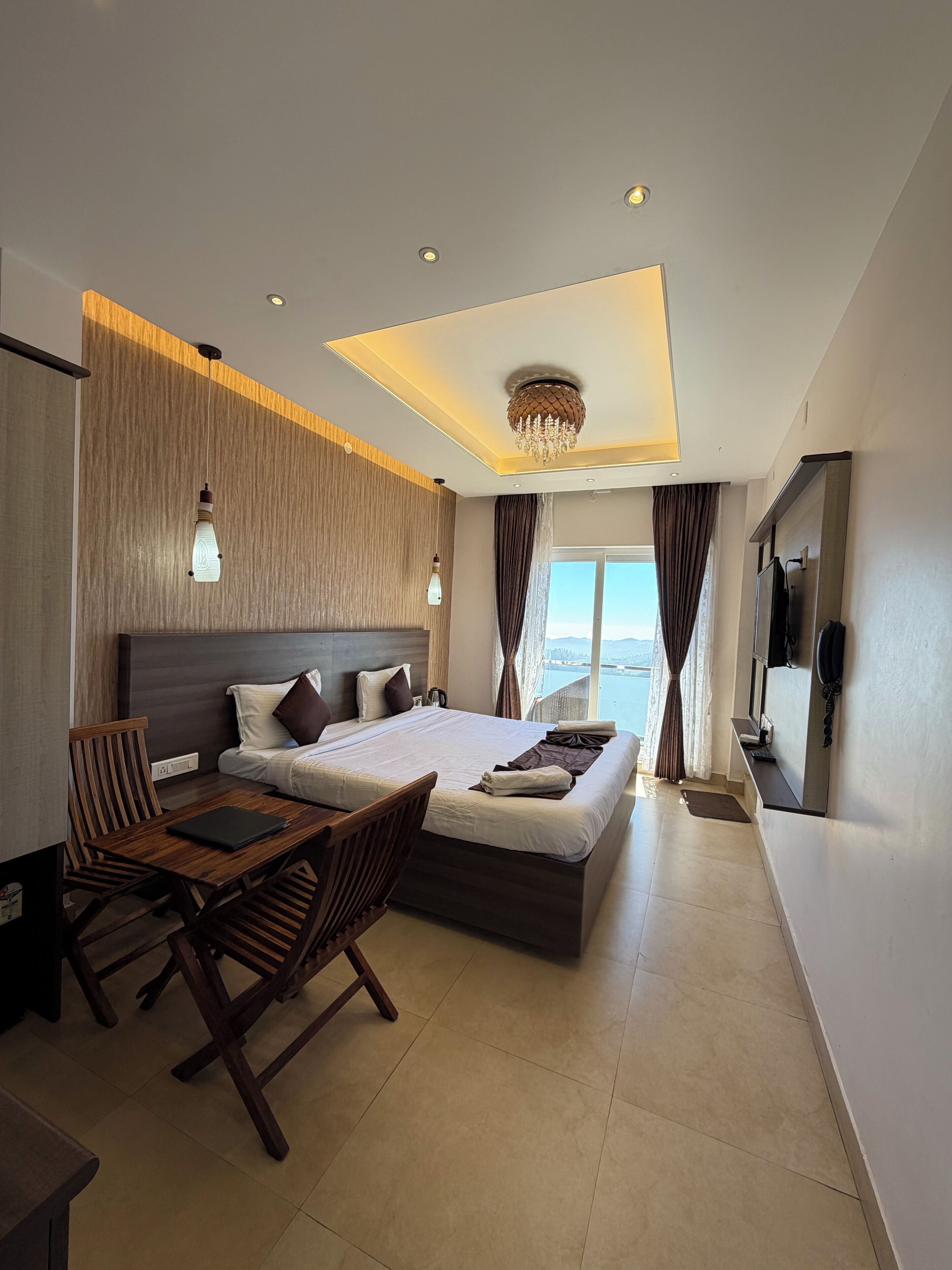 Un hotel moderno con una cama grande, muebles de madera, un candelabro y vistas al mar.