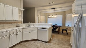 A kitchen with white cabinets, a dishwasher, and a dining area with a table and chairs.