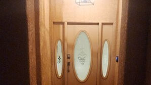 A hotel entrance with a stone facade, a central light fixture, and two doors with oval glass panels.