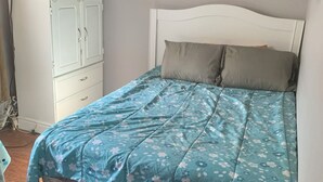 Ein Schlafzimmer mit einem Bett, einem Fernseher auf einem Schrank und zwei Wandbildern.