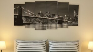 Ein Hotelzimmer mit einem Bett, das mit gestreifter Bettwäsche ausgestattet ist, einem Stadtbildgemälde darüber und zwei Nachttischlampen.