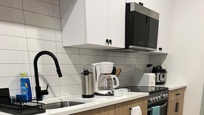 Eine moderne Küche mit Geschirrspüler, Kaffeemaschine, Mikrowelle und Backofen.