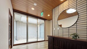 A hotel lobby with a wooden ceiling, a reception desk, and a large glass door leading to a balcony. - Eight Valley Nakamachi (Hiroshima)