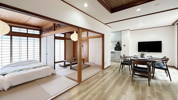 A traditional Japanese-style room with tatami flooring, a low wooden table, and a TV mounted on the wall. - Eight Valley Nakamachi (Hiroshima)