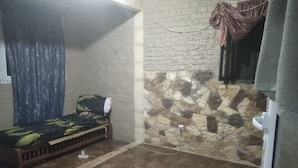 Ein kleiner Raum mit einem Bett, einer Steinwand und einem gefliesten Boden.