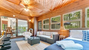 Interno di una baita in legno con un letto, un divano e zona pranzo.