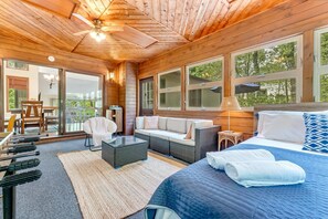 En stuga med träpanel på insidan, inredd med en säng, en soffa och en matplats.