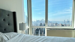 Camera d'albergo con un letto grande, vista sulla città e una lampada moderna.