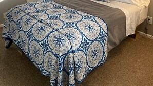 Een slaapkamer met een bed, een raam met gordijnen, een deur en een aan de muur hangend schilderij.