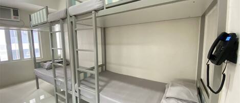 A bunk bed room with a telephone and a window.